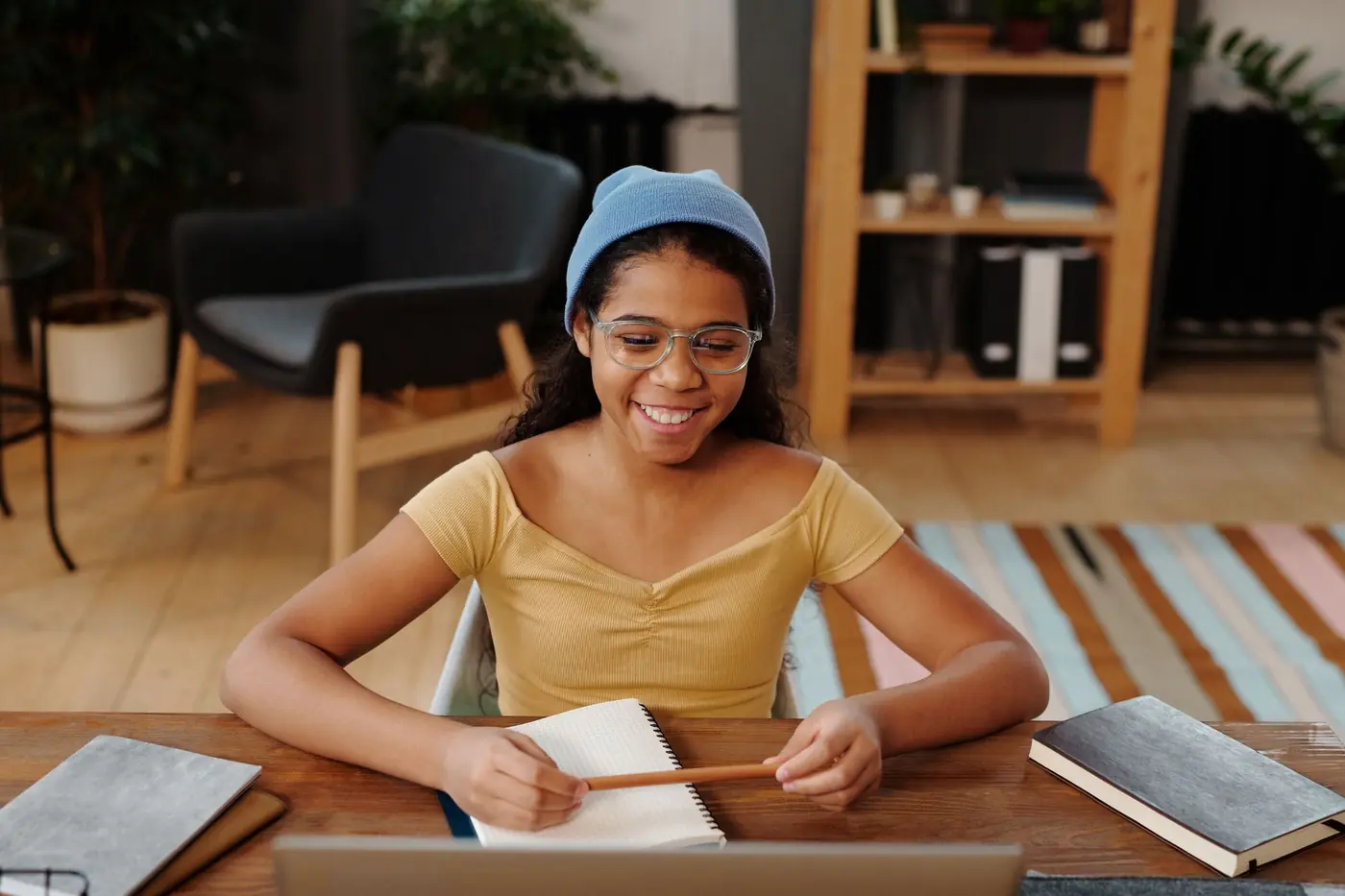 A teenage girl in glasses smiling as she writes in her notebook
