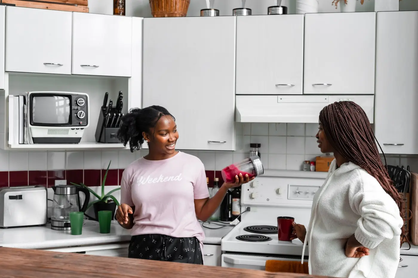 A young person making a drink with a support worker in a modern kitchen